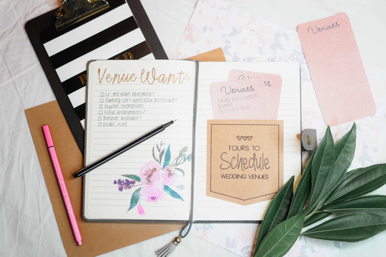 Services Flat lay of wedding planning materials including a journal, leaves, and stationery.